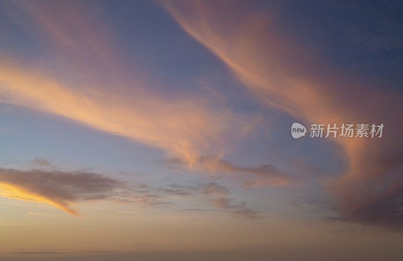 夕阳下的天空是柔和的颜色，粉橙色和浅蓝色