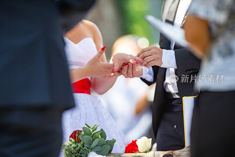 年轻的夫妇在祭坛前准备结婚，新郎把戒指放在新娘手上的照片