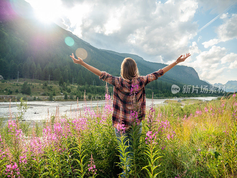 日出时，河边的野花场上，欢呼的妇女张开双臂