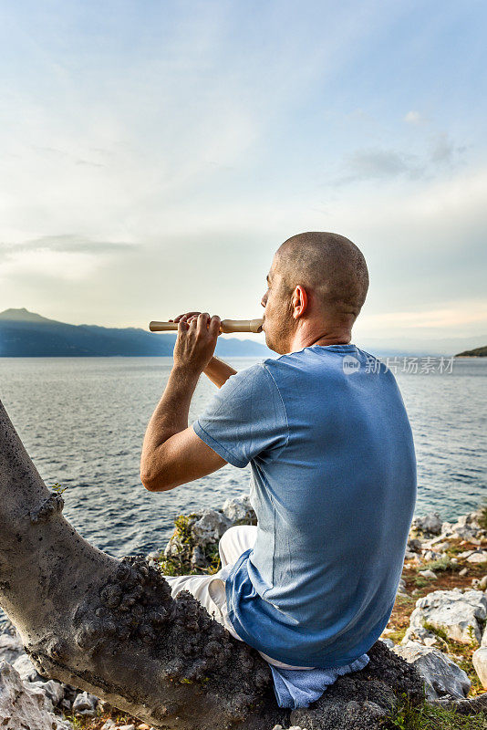 在海边，一个人吹着木笛看日落