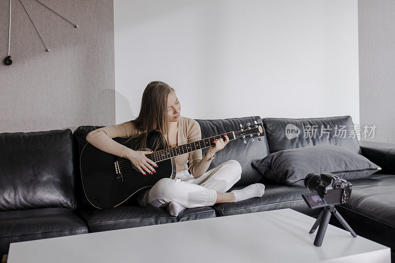 年轻美丽的女性是在她的家里，弹吉他