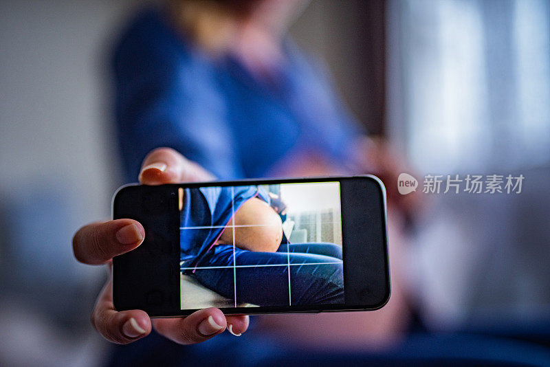 一名孕妇在给自己的肚子拍照。