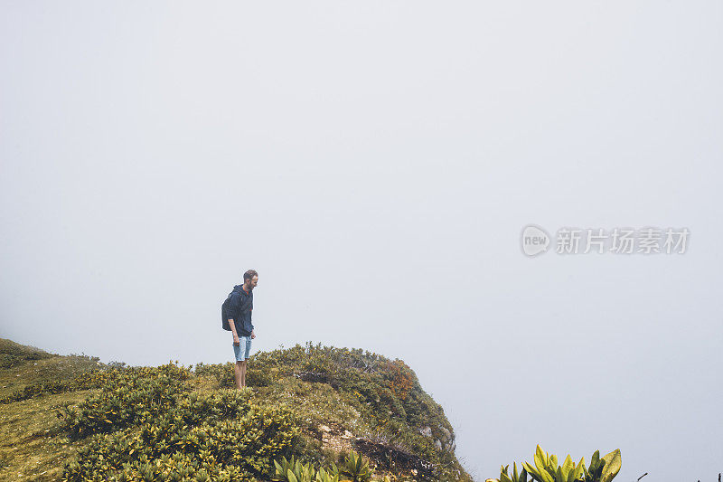 一个背包旅行者站在山的边缘欣赏风景