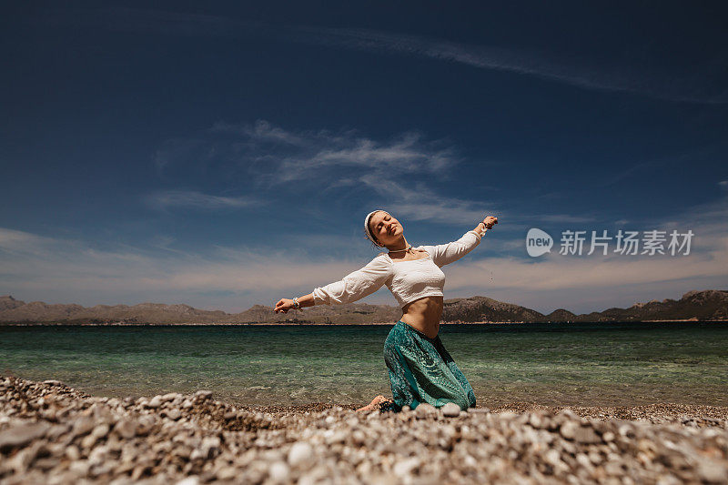 精神上的女人在阳光明媚的海滩上快乐地跳着精神上的神圣舞蹈