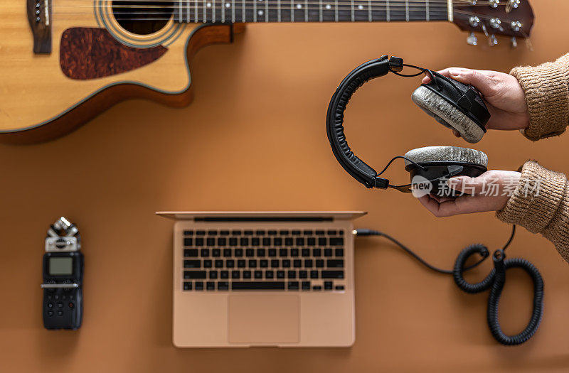音乐背景与耳机在女性手中，录音机，笔记本电脑和吉他。