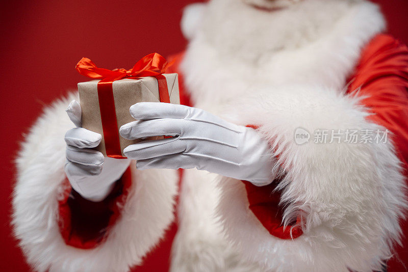 圣诞老人手里拿着一个红色背景上的小礼盒