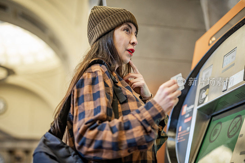 一个漂亮的成熟女人在巴塞罗那的地铁站使用自动取款机