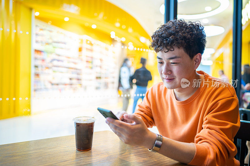 亚洲年轻帅哥在咖啡店用智能手机