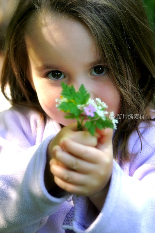 一个黑发的小女孩，手里拿着花