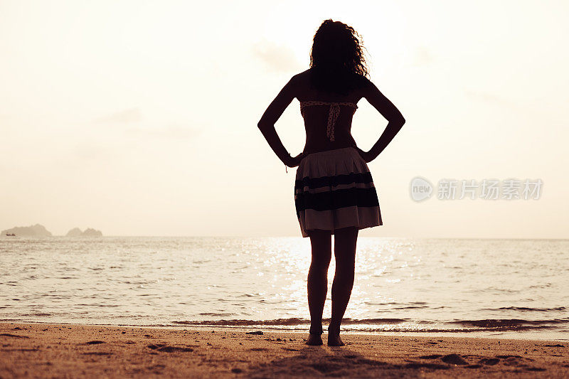 年轻女子站在海滩上望着大海