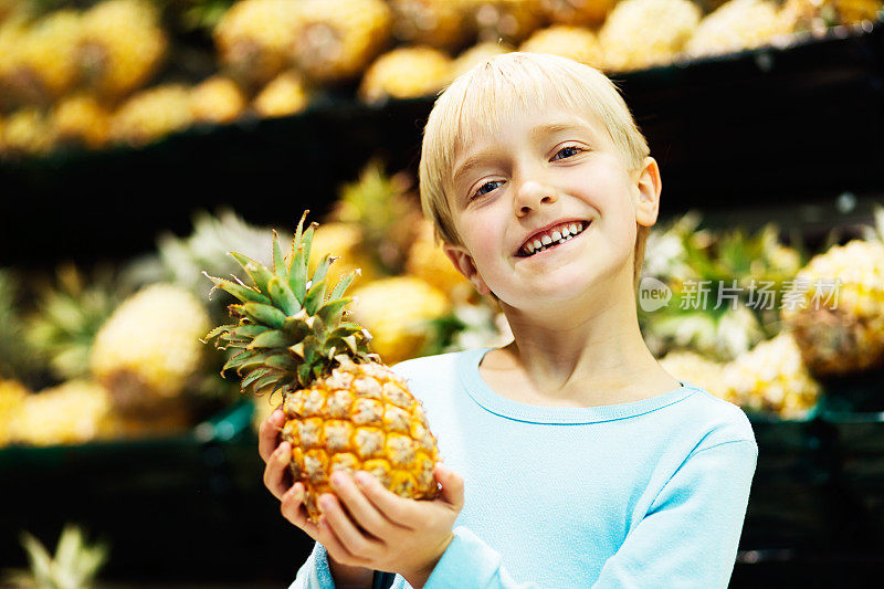 可爱的，微笑的小女孩与菠萝在超市