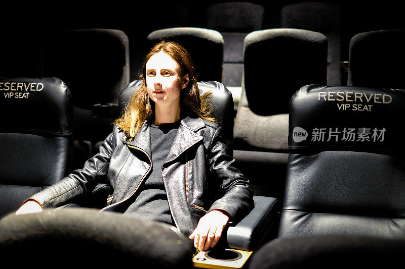一个年轻的白人女人独自坐在电影院