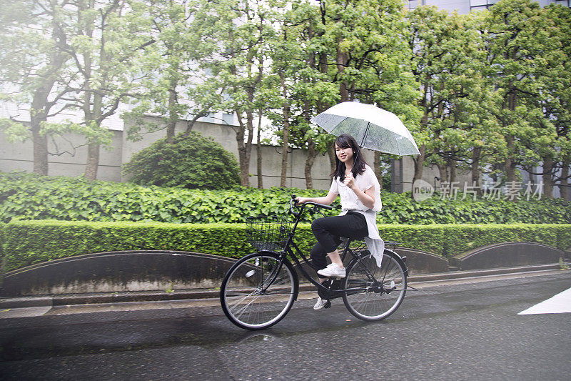 一个年轻的日本女人在东京的雨天骑自行车