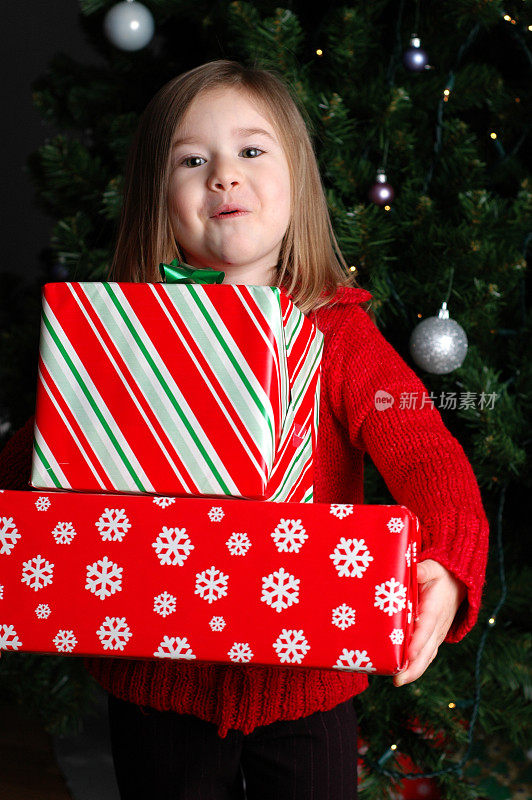 兴奋的小女孩拿着圣诞树上的圣诞礼物