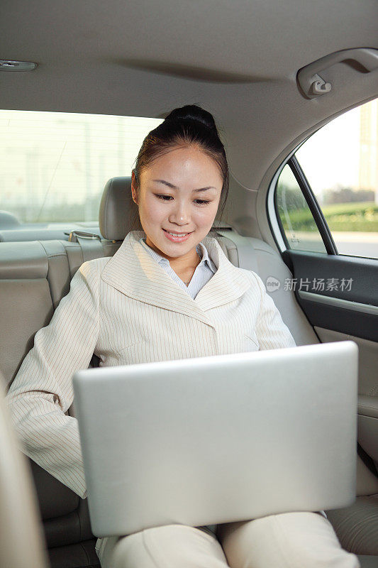 年轻女商人在车上使用笔记本电脑
