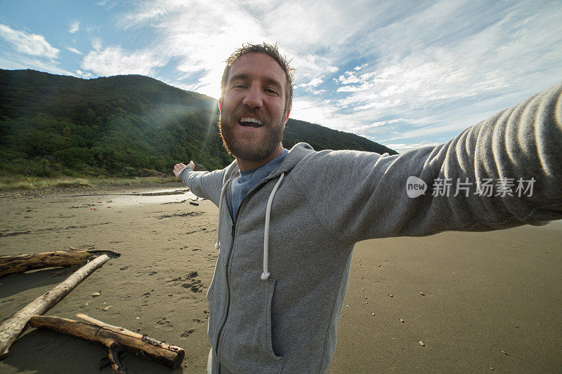 一名兴高采烈的男子在狂野的海滩上自拍