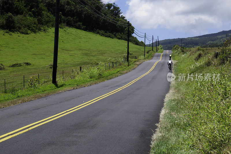 两个骑自行车的人在乡村的山路上