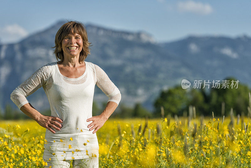 幸福成熟的女人站在鲜花草地上