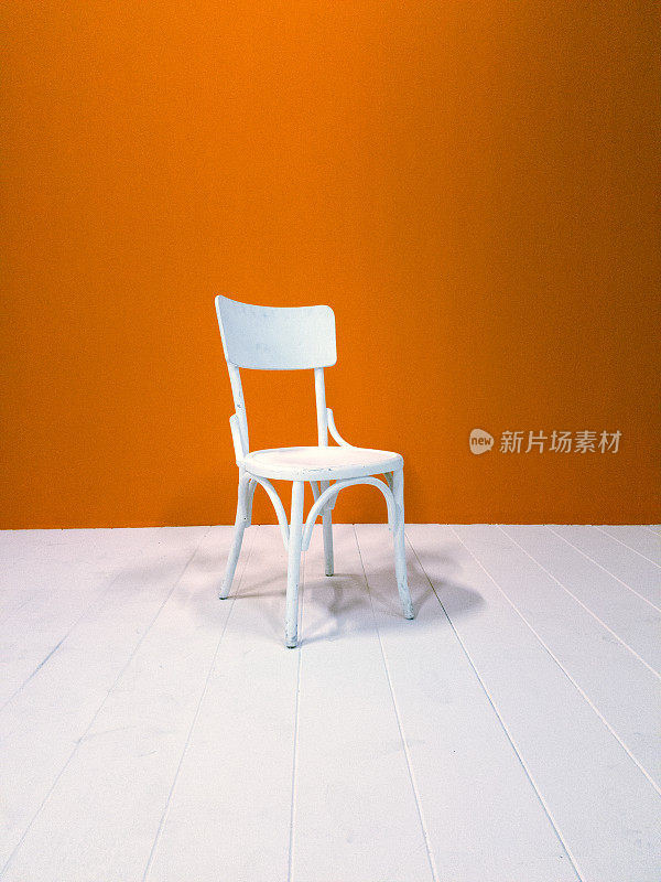 白色的木椅和橘色的墙