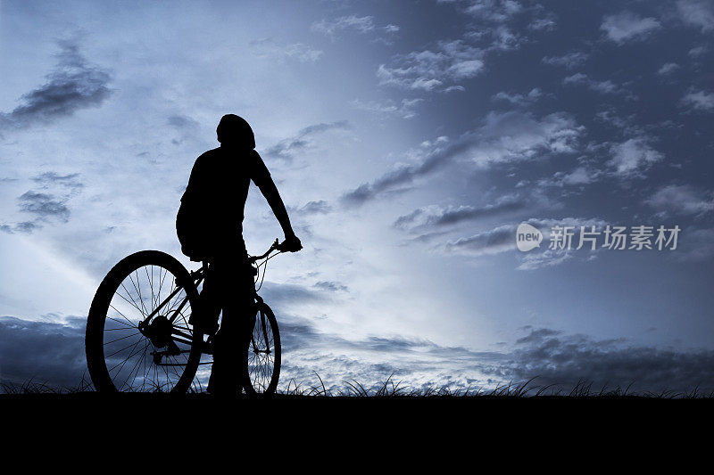 在夜幕降临的田野里骑自行车的人