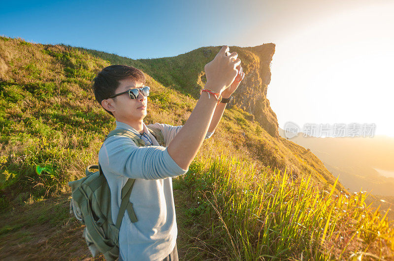 年轻的旅行者站在山上望着夕阳。