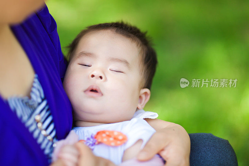 近距离的母亲拥抱婴儿女孩在户外的自然