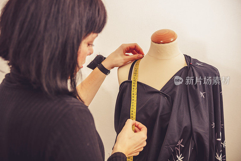 时装设计师在裁缝的假人上测量服装形式