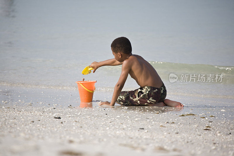 小男孩在海滩上装桶