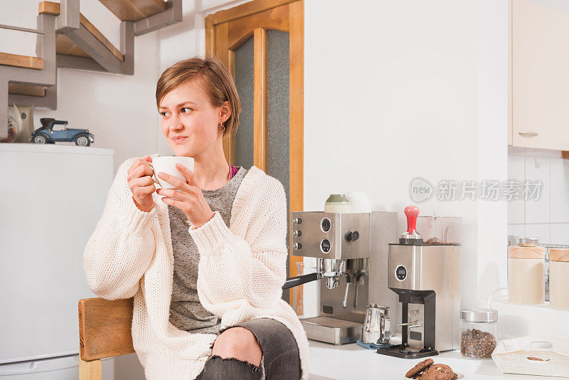 年轻可爱的女人在家里享受一杯咖啡