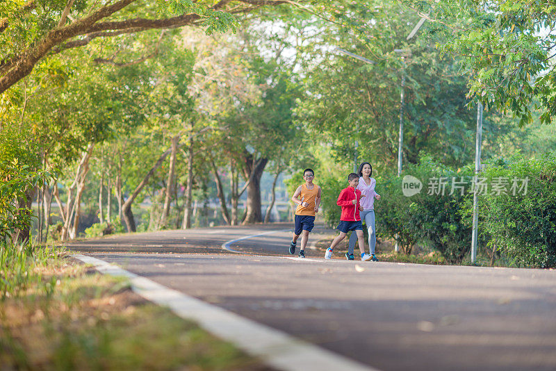 家庭运动快乐活跃的母亲和孩子在户外慢跑，在森林里跑步