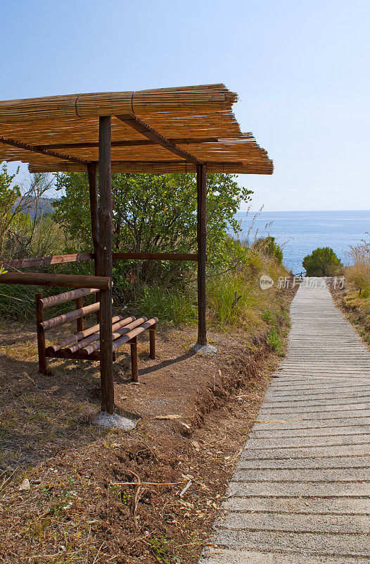 卡拉布里亚:通向阿科马格诺海滩的小路上的一条长椅，大拱门海滩，一个隐藏的小海湾，在几个世纪的海浪中形成了一个天然的拱门