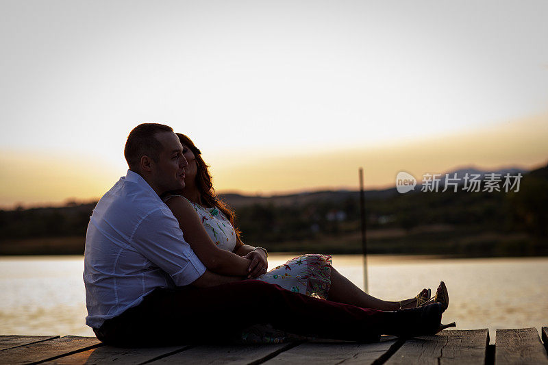 浪漫的情侣在湖边欣赏日落