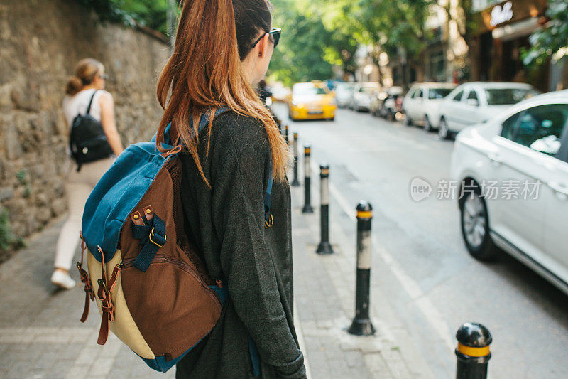 一个背着背包的年轻女游客在大城市里等出租车。的旅程。观光。旅行。