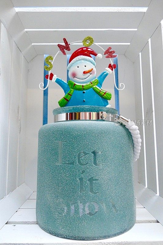 圣诞老人雪人站在一个蓝色的花瓶上，上面写着:让它下雪吧