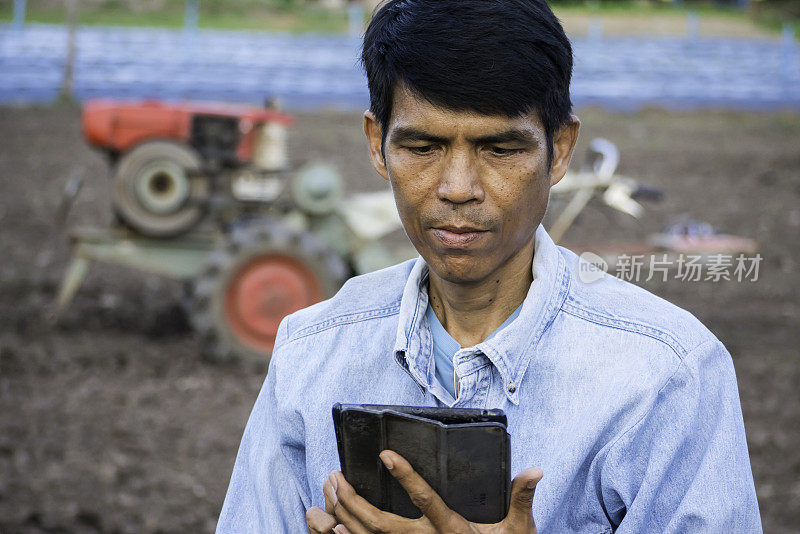 亚洲农民在农业中使用平板电脑，以机器为背景