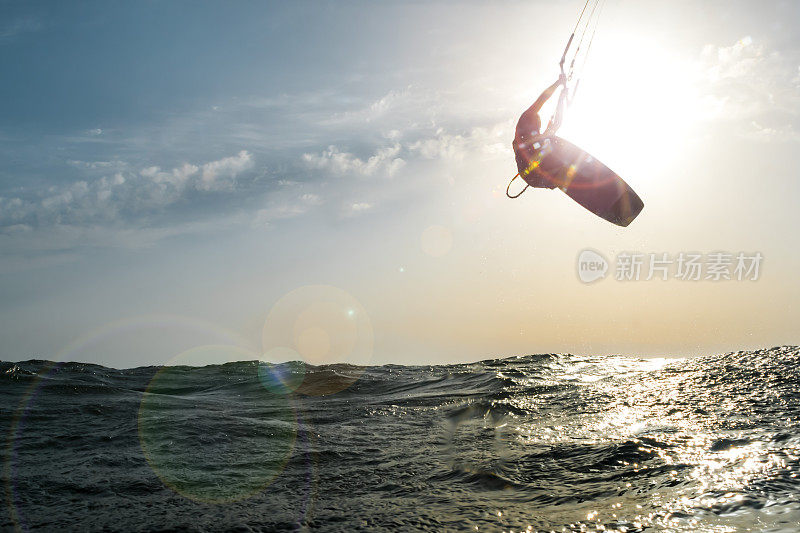 冲浪者在夕阳下跳跃在金色的海面上