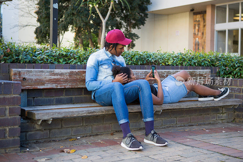 一对年轻的黑人夫妇正在用手机放松