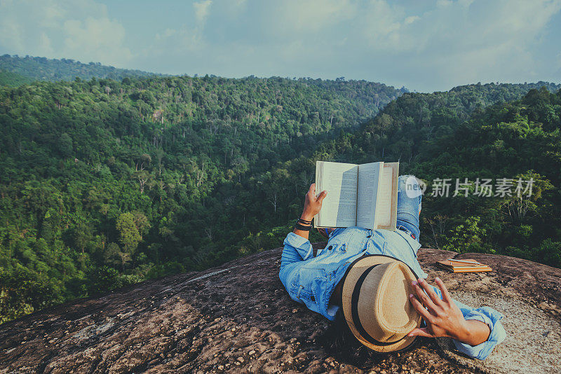 亚洲男人在假期旅游放松。睡觉，放松，在岩石峭壁上看书。在山顶上。在泰国