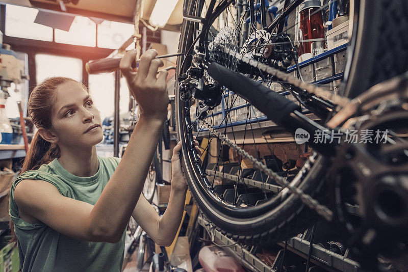 女自行车修理工正在车间里修一辆自行车