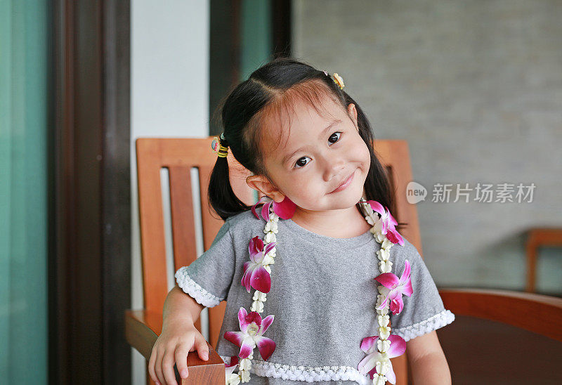 微笑的小亚洲女孩的肖像与欢迎兰花花花环。
