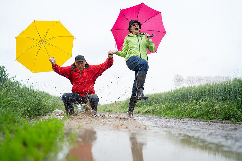 老夫妇有乐趣在雨天跳进水坑