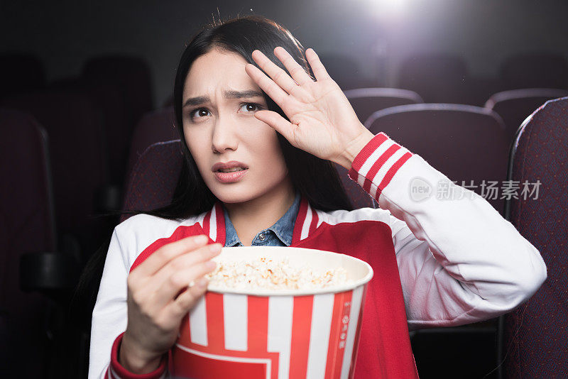 受惊吓的亚洲女孩在电影院吃爆米花看电影