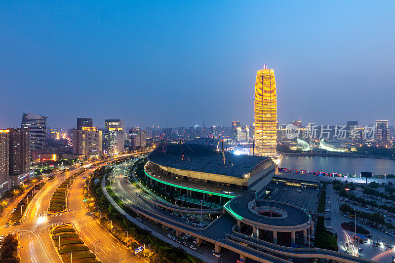 环形道路被湖边的摩天大楼包围，夕阳下的城市天际线。郑州,中国