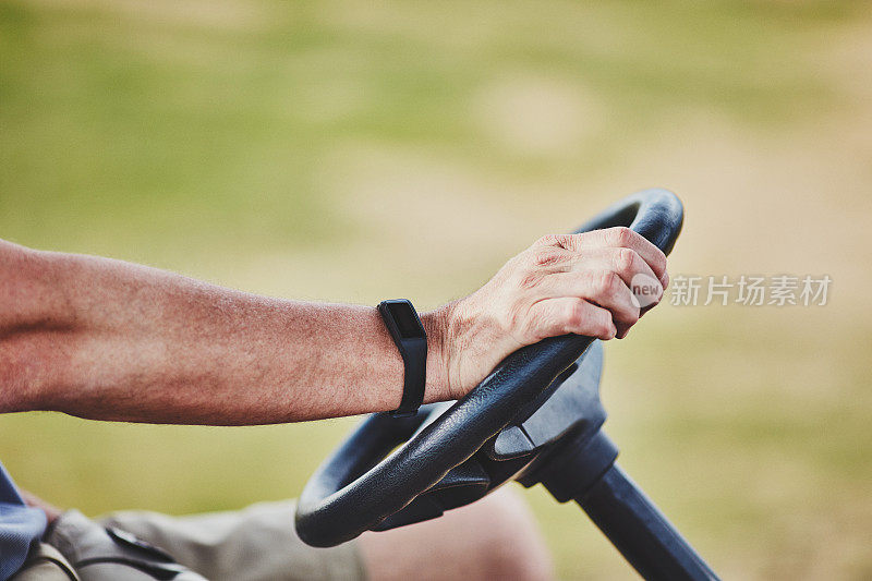 男性高尔夫球手佩戴健身追踪器驾驶高尔夫球车