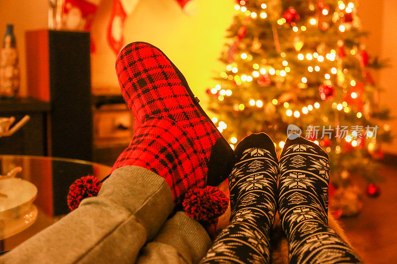 一对夫妇穿着冬天的袜子，在家里的圣诞树上放松