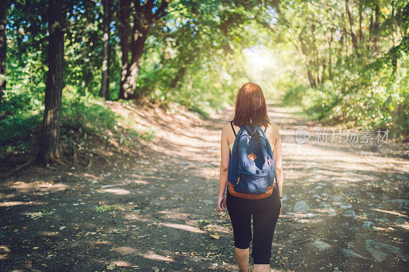 背包女旅行者在森林里行走。