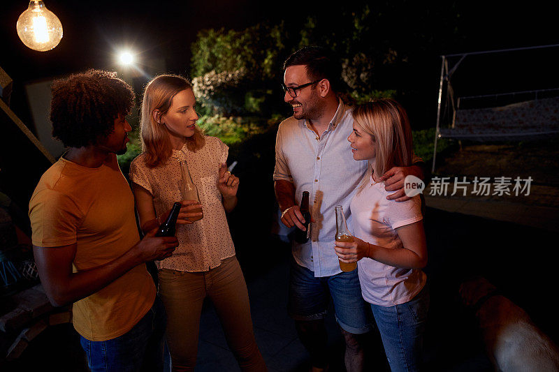 愉快的朋友们晚上在露台上举行饮酒聚会。