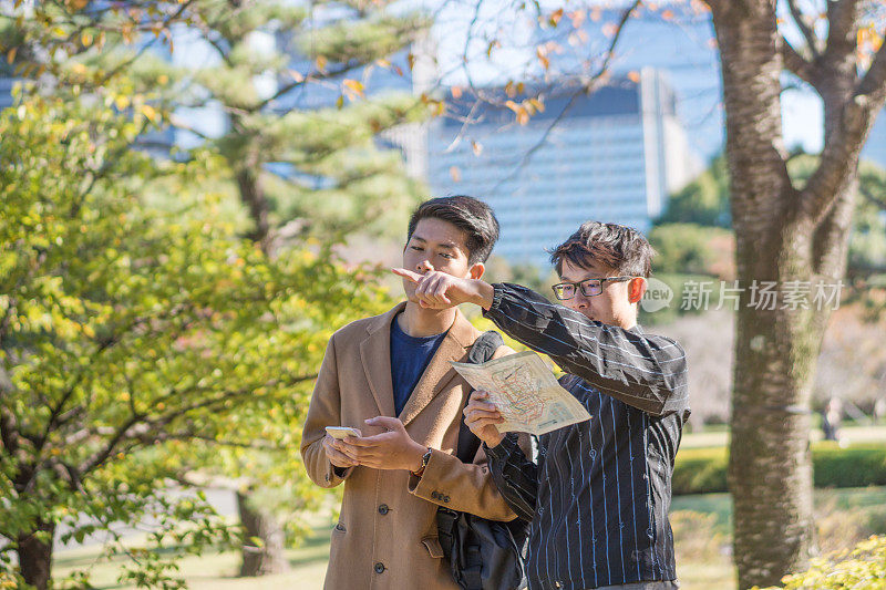 年轻的亚洲男子和日本朋友寻找旅游地点使用手机和花时间在亚洲旅行