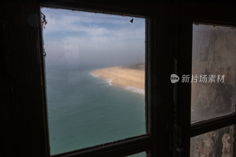 透过一扇旧窗户看到的海滩景色