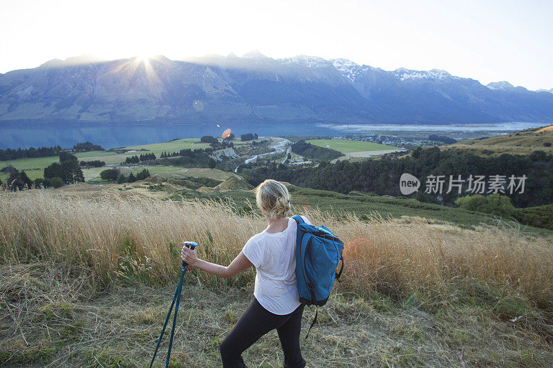 日出时分，女徒步旅行者在山谷上空放松